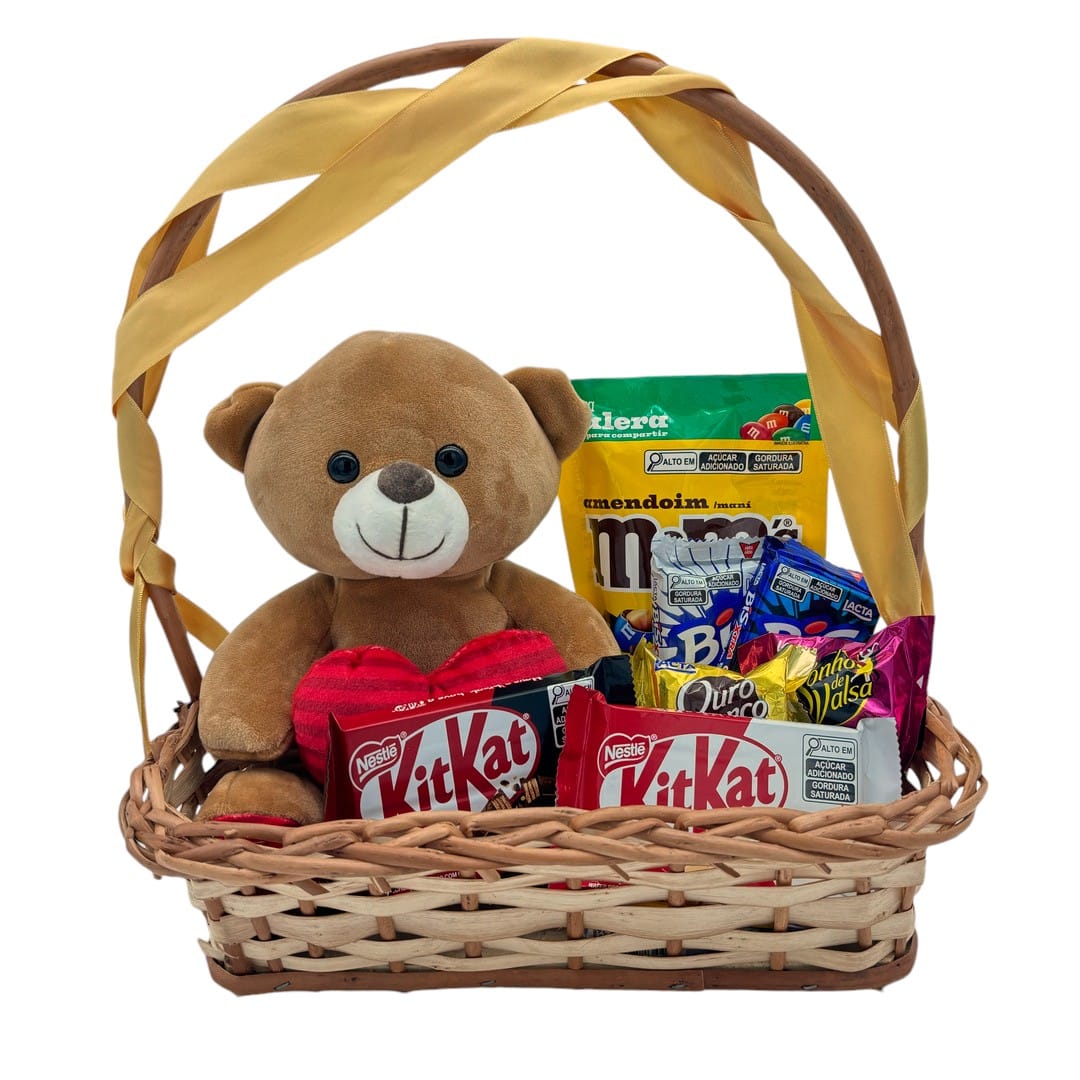 Cesta de palha com laço, pelúcia de ursinho, kit kat, bis e doces variados fundo branco